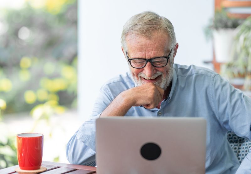 Älterer Herr sitzt zu Hause vor dem Laptop