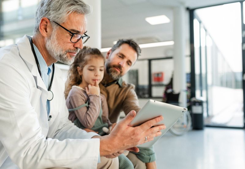 Arzt bespricht im Krankenhaus einen Befund mit Vater und Tochter