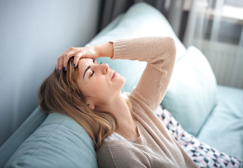 Junge Frau sitzt erschöpft auf dem Sofa